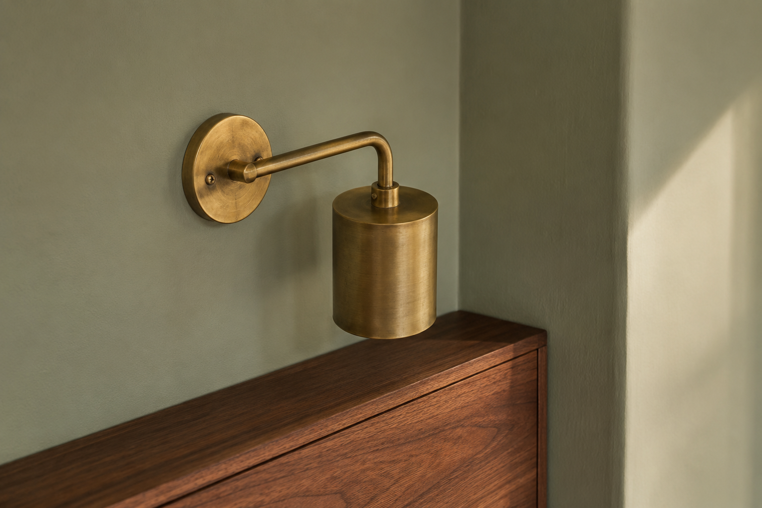 Warm gray-based green wall paired with a brass sconce and walnut wood