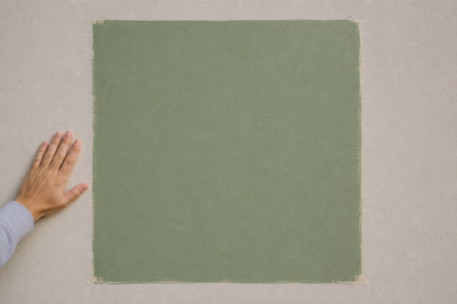 A large painted green sample square taped to a wall for testing