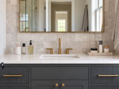 A bathroom vanity counter split into a small daily-use zone and a contained occasional-use tray, brass hardware against graphite cabinetry.