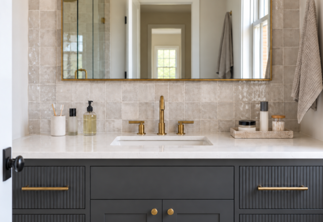 A bathroom vanity counter split into a small daily-use zone and a contained occasional-use tray, brass hardware against graphite cabinetry.