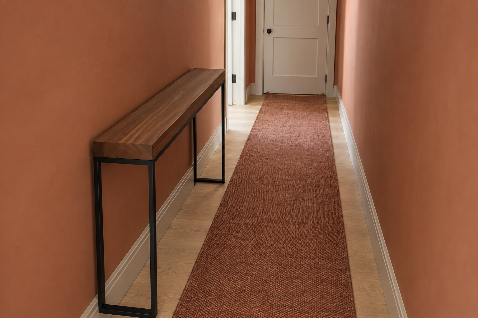 An elevated view down a narrow hallway showing a black steel console table's depth against the walking space remaining beside it.