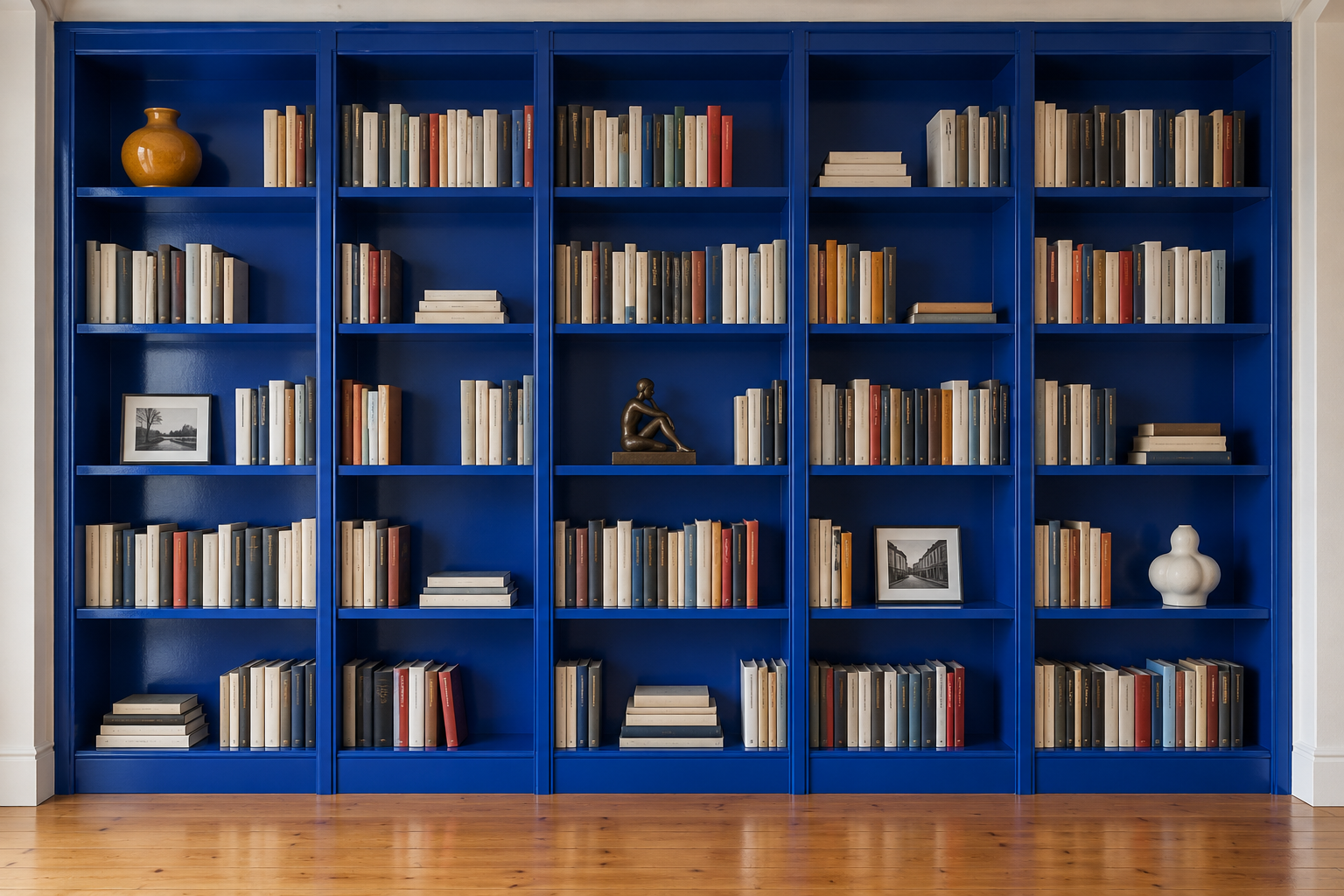 A cobalt bookcase with three objects placed on a diagonal among rows of books.