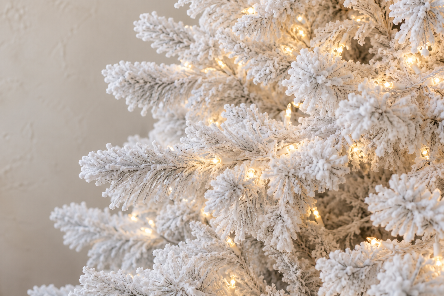 Warm white lights on white wire along the branches of a flocked Christmas tree.