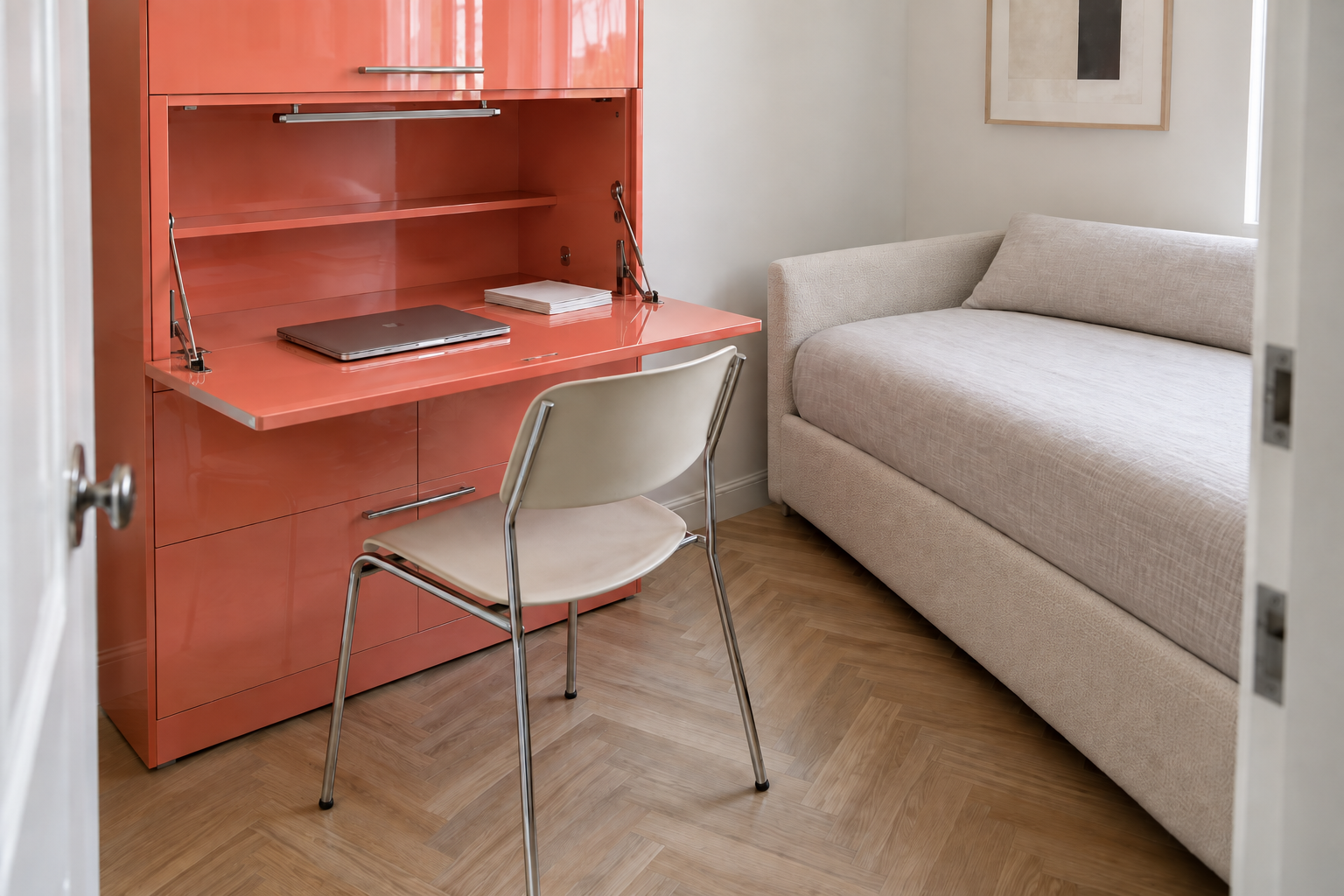 A glossy coral lacquer cabinet opened to reveal a fold-out desk surface, in a small apartment room with a herringbone floor.