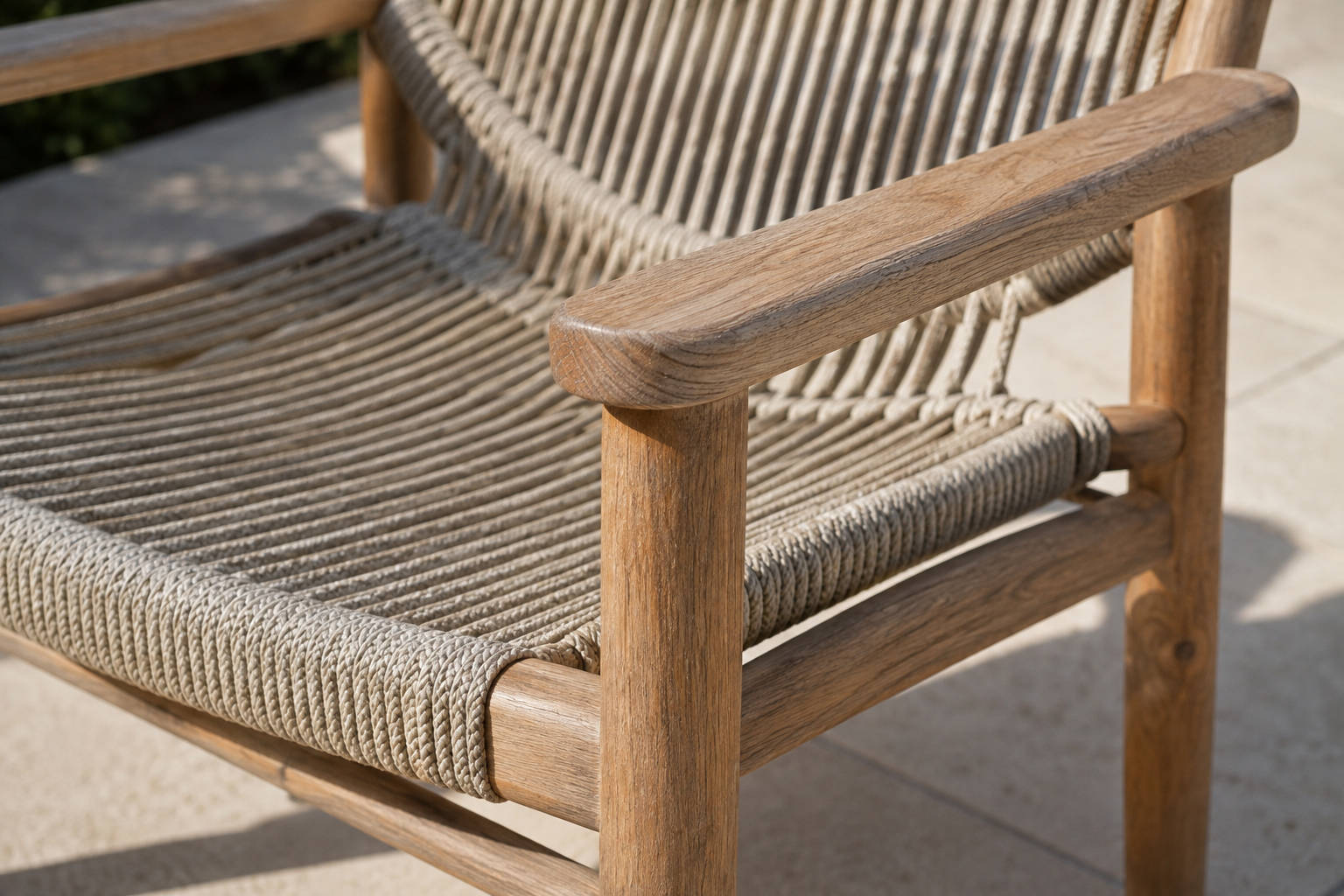 Close detail of a rope-and-teak lounge chair built for low-maintenance outdoor use