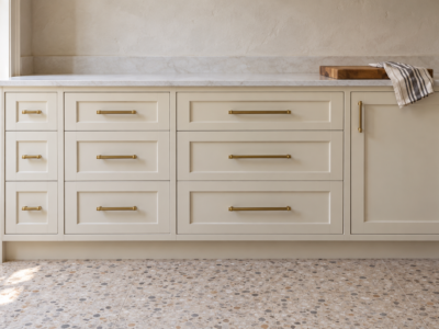 Cream Shaker kitchen drawers in three widths, each with a brass bar pull about a third as long as the drawer is wide.