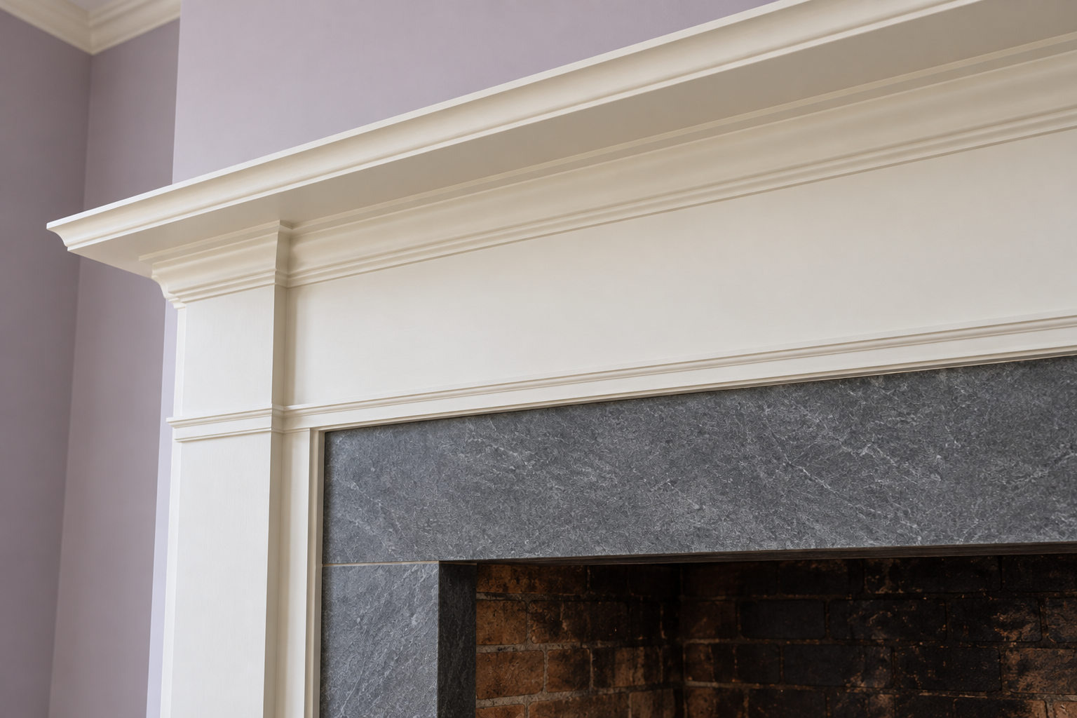 A band of dark soapstone between the top of a fireplace opening and the white wood mantel shelf above it.