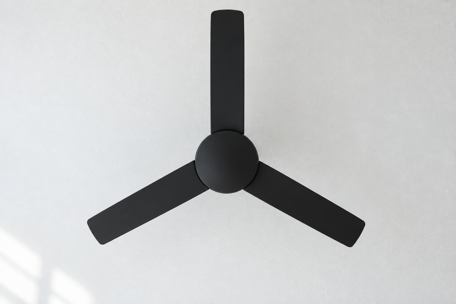 A black ceiling fan with three blades seen from directly below against a white ceiling.