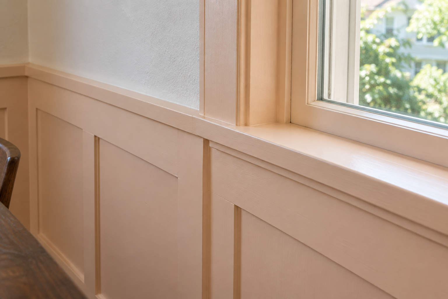 A peach wainscot cap meeting a windowsill at the same height, forming one line along the wall.