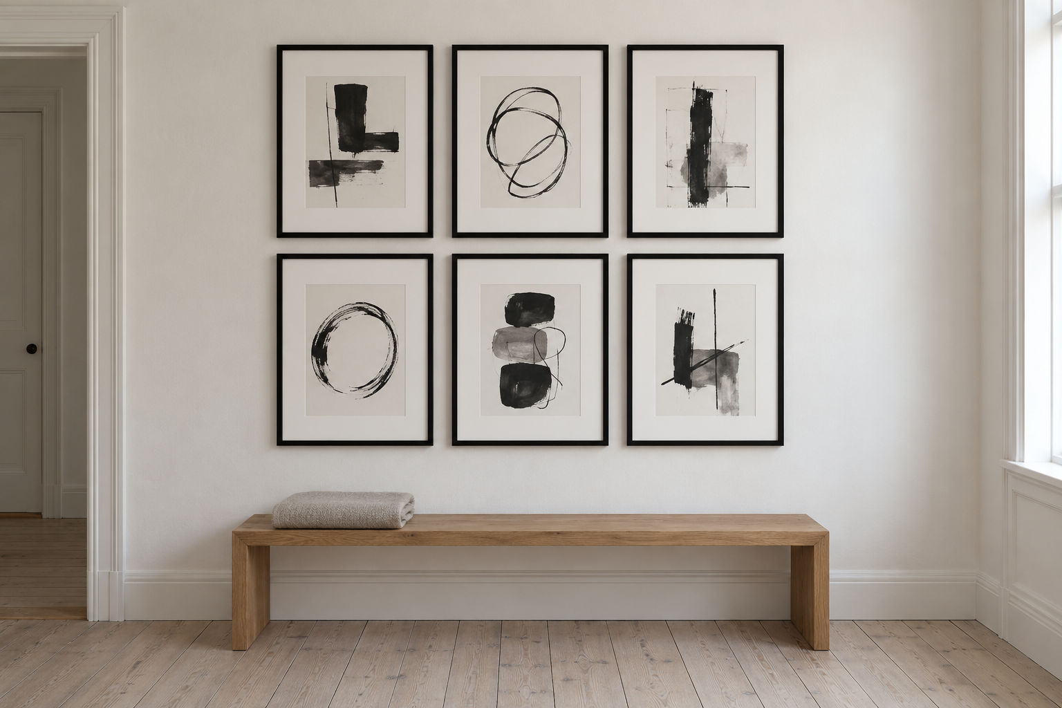 Six identical black frames with white mats hung in a grid of three columns and two rows above an oak bench.