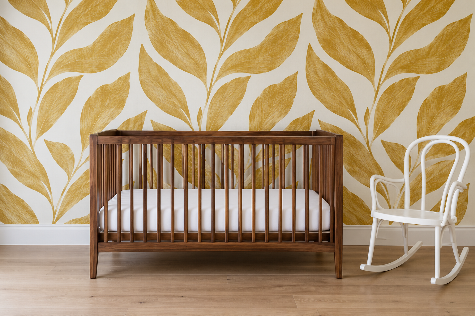 A nursery papered in a large ochre leaf pattern on white, with a bare walnut crib in front of it.
