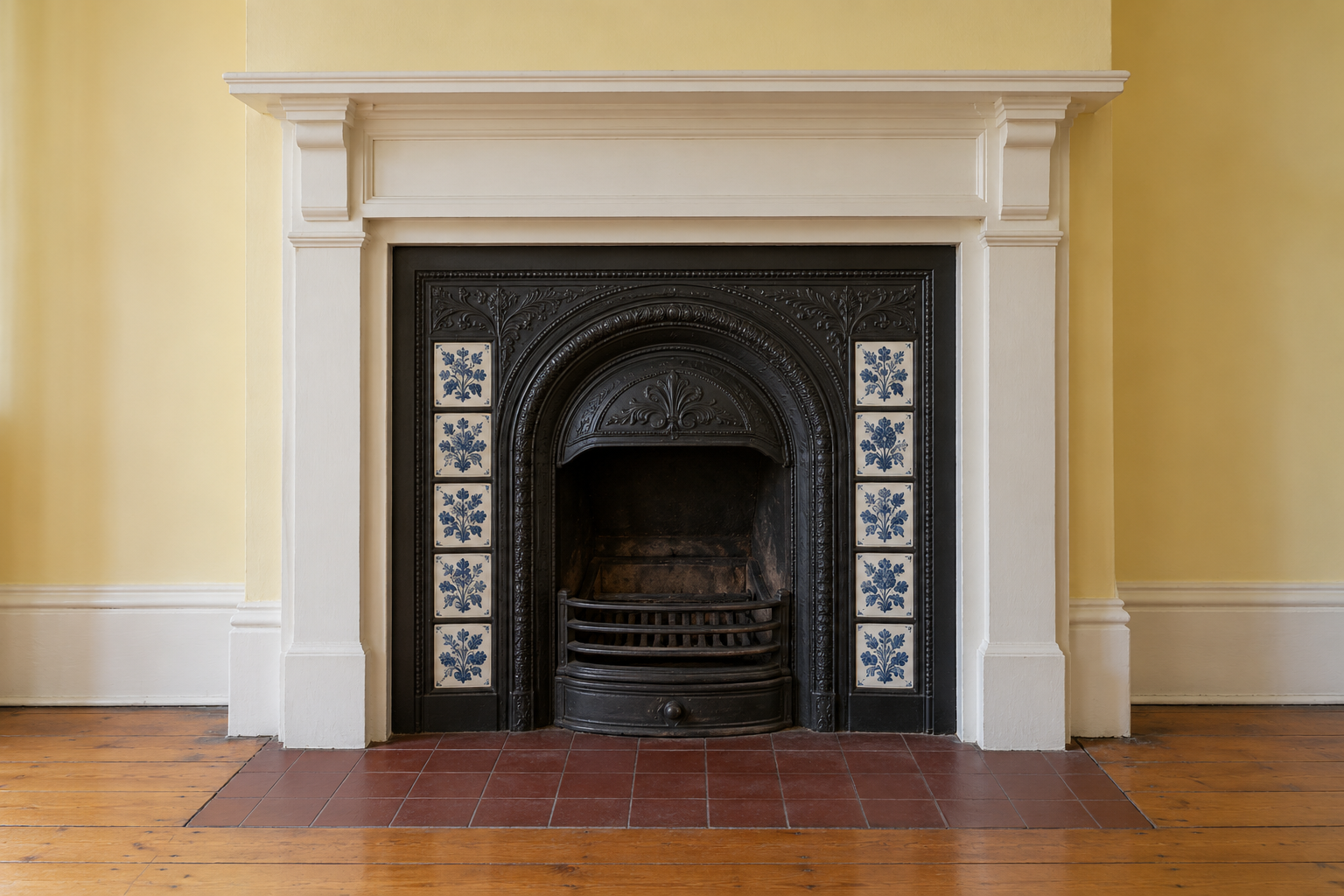A black cast iron fireplace insert with strips of blue and white patterned tiles down each side, in a room with butter yellow walls.