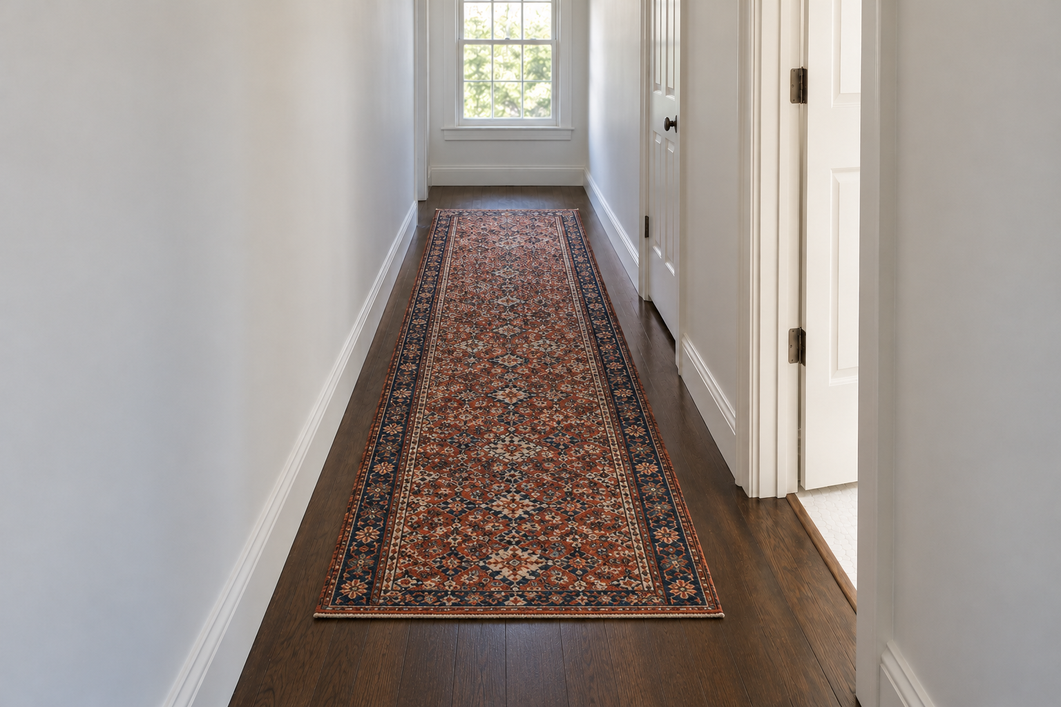 A long patterned wool runner in brick red and indigo on a dark wooden hallway floor, with a strip of bare floor along each wall.