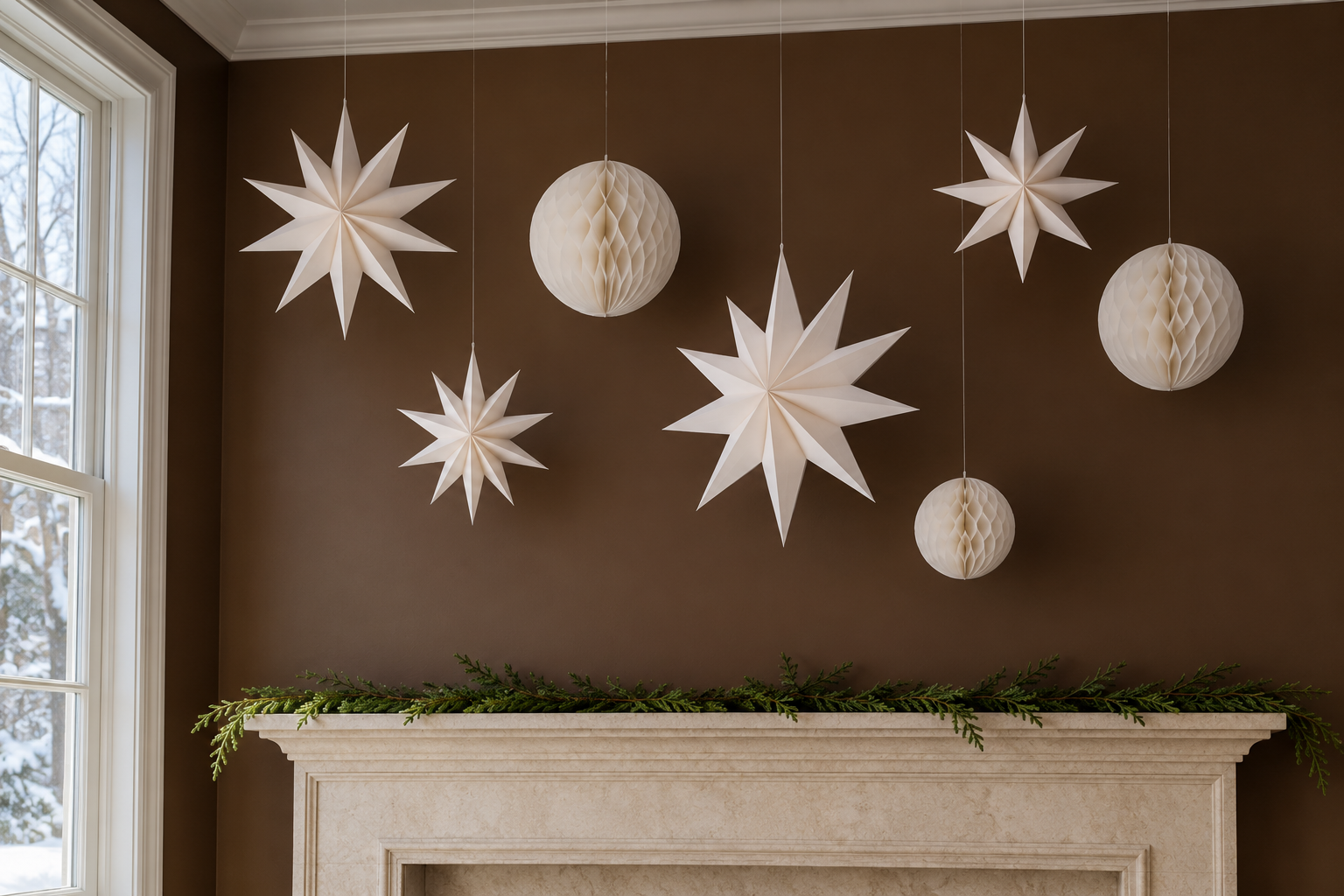 White folded paper stars and honeycomb balls hanging on threads at different heights above a mantel, against a chocolate brown wall.