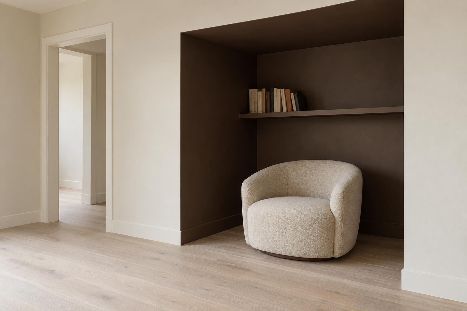 A recess painted chocolate brown, holding an oatmeal barrel chair, set into the wall of a pale stone-colored room.
