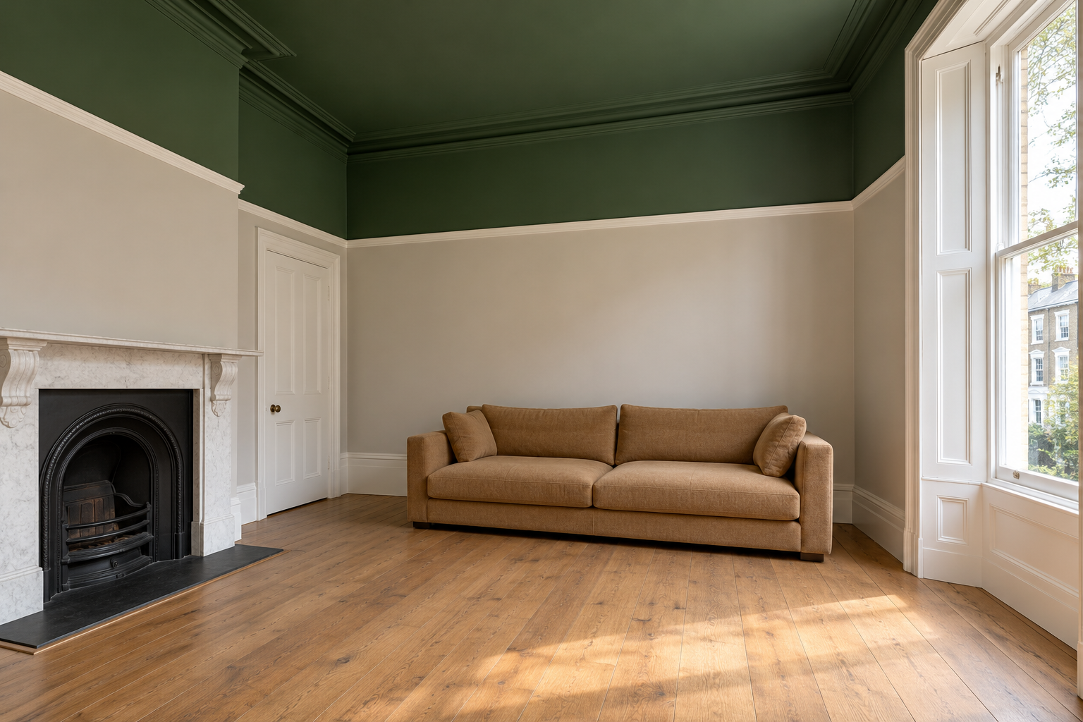 A living room with a deep green ceiling whose color runs down the walls to a picture rail, with pale stone walls below and a low sofa.