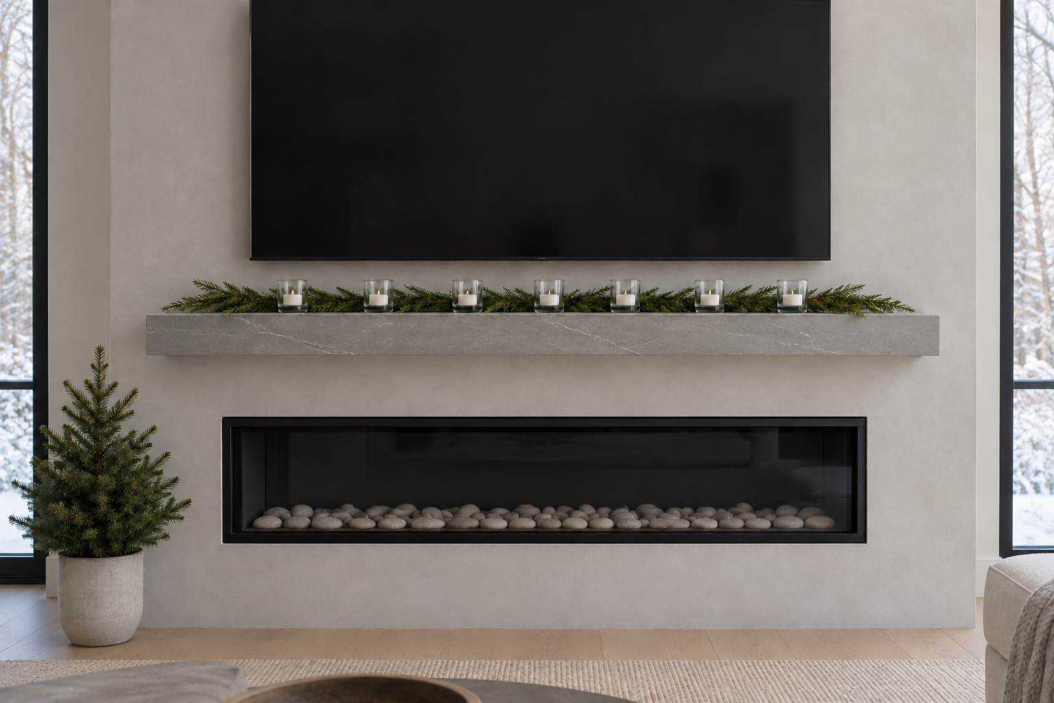 A flat line of evergreen and low glass lights on a stone shelf under a wall-mounted television above a modern fireplace.