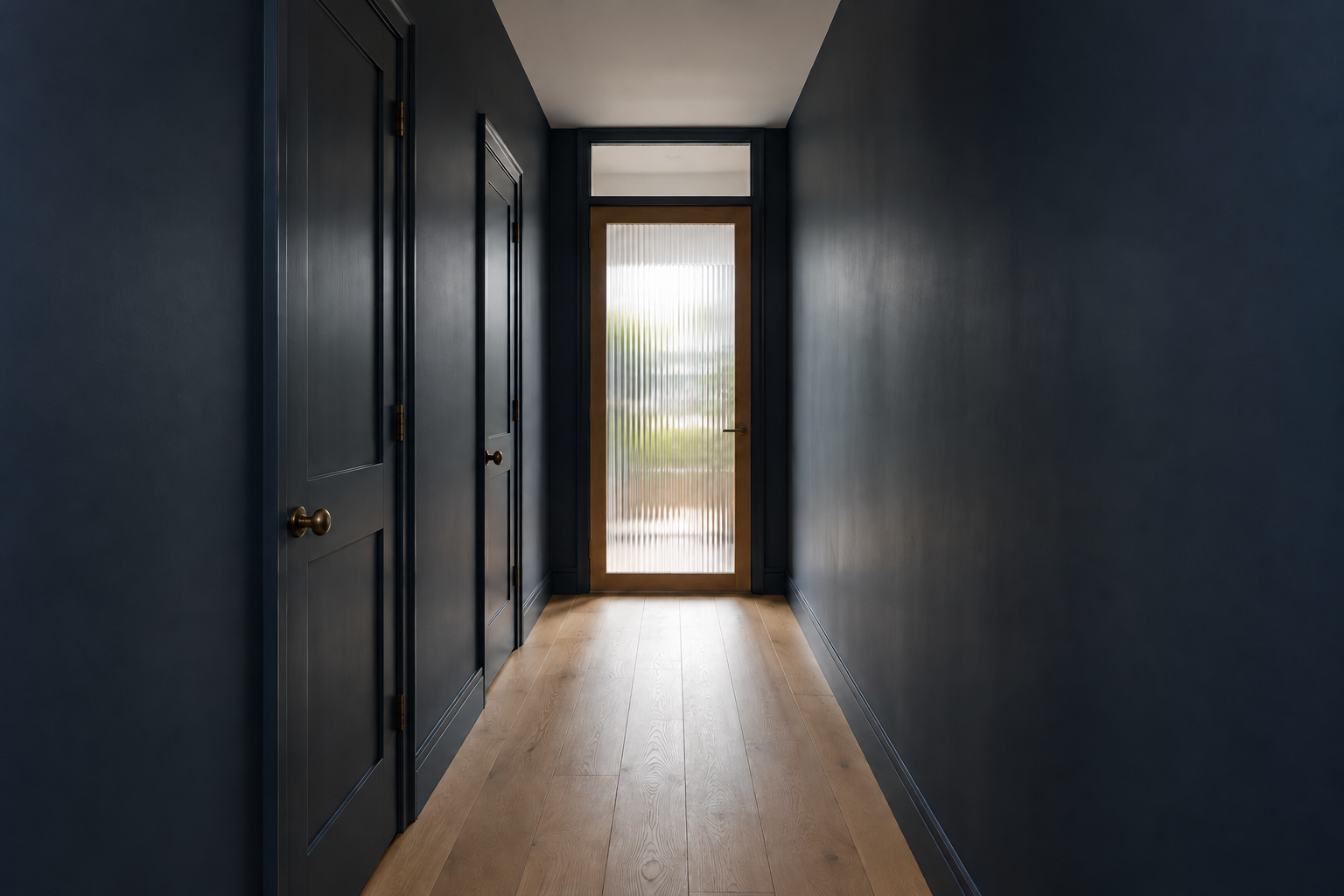 A windowless hallway with dark blue walls, lit by daylight coming through a reeded glass door at the far end.
